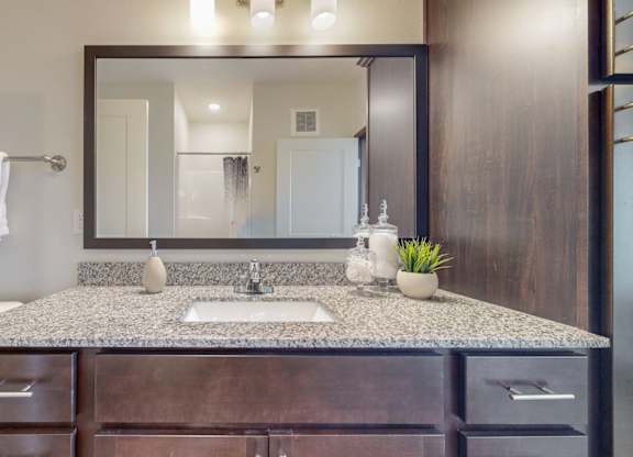 A bathroom with a granite countertop and a large mirror. at Lake Jonathan Flats, Chaska, MN, 55318