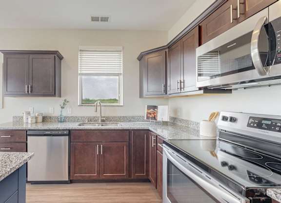 A kitchen with a granite countertop and stainless steel appliances. at Lake Jonathan Flats, Chaska, Minnesota