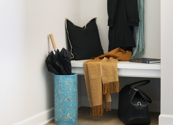 a hallway with a bench with a hat and bags on it and a coat rack