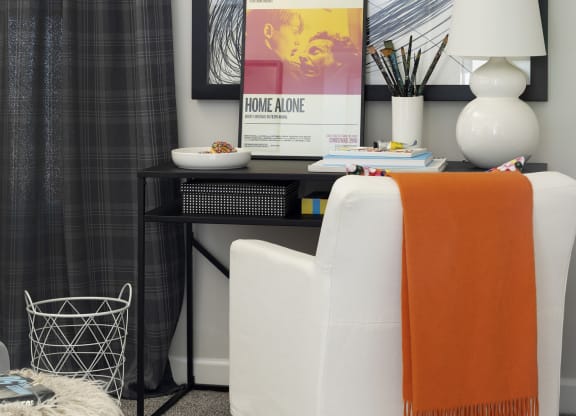 a home office with an orange and white chair and a black desk with a computer