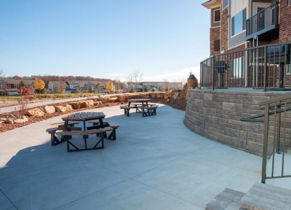 Large Concrete Patio in Back Exterior of Property in Carver, MN with Picnic Tables and Grilling Stations