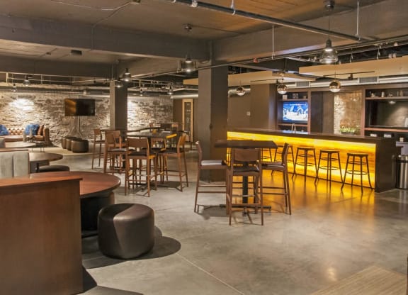 Open Gathering Space with Couches, Tables and a Bar at Apartment in Minneapolis