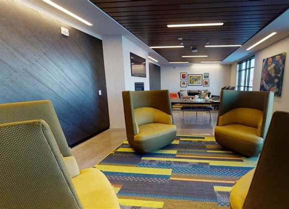 A room with a blue and yellow carpet and chairs at The Bessemer at Seward Commons Apartments, Minnesota, 55404