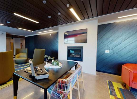 A modern dining room with a wooden table and chairs at The Bessemer at Seward Commons Apartments, Minnesota