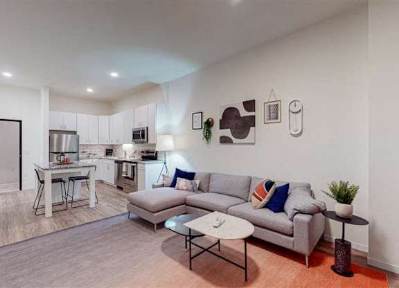 A modern living room with a grey sofa and a coffee table at The Bessemer at Seward Commons Apartments, Minneapolis, 55404