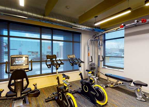 A room with exercise equipment and a window overlooking a city at The Bessemer at Seward Commons Apartments, Minneapolis