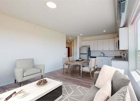 A modern living room with a grey couch and a coffee table at The Bessemer at Seward Commons Apartments, MN, 55404