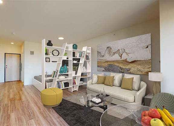 A modern living room with a white couch and a painting on the wall at The Bessemer at Seward Commons Apartments, Minneapolis, Minnesota