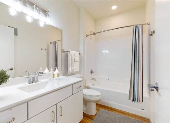 A white bathroom with a toilet, sink, and shower at The Bessemer at Seward Commons Apartments, Minneapolis, MN,  55404