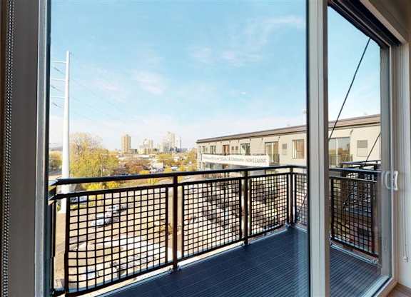 A balcony with a black railing and a view of a cityscape at The Bessemer at Seward Commons Apartments, Minneapolis, 55404
