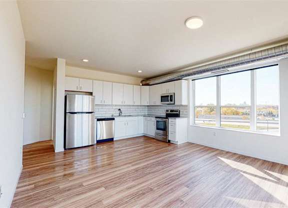 A spacious kitchen with white cabinets and a wooden floor at The Bessemer at Seward Commons Apartments, Minneapolis