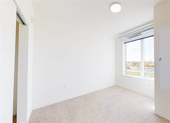 A room with a window and a carpet on the floor at The Bessemer at Seward Commons Apartments, Minnesota