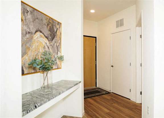 A hallway with a painting on the wall and a bench with a tree on it at The Bessemer at Seward Commons Apartments, Minneapolis, Minnesota