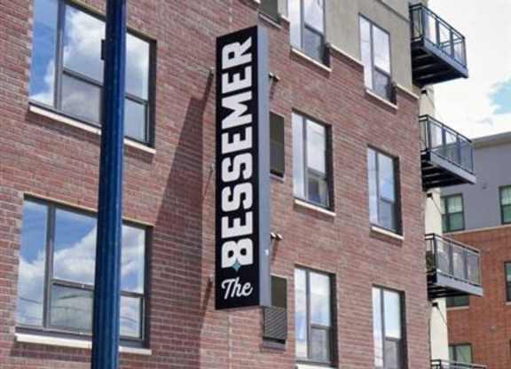 A street lamp stands in front of a building with the word at The Bessemer at Seward Commons Apartments, Minneapolis