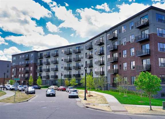 A large apartment building with a parking lot in front at The Bessemer at Seward Commons Apartments, Minneapolis, 55404