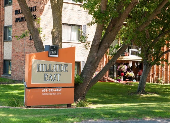a sign that says hillside east in front of a brick building