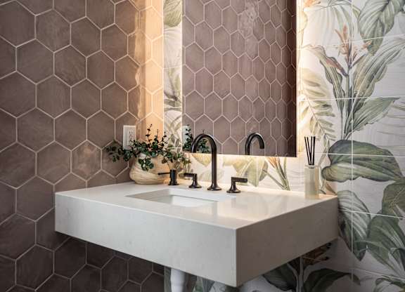 A bathroom with a white sink and a mirror with a wooden frame.