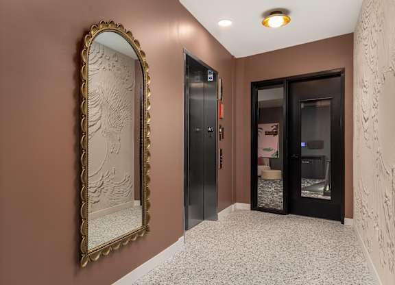 A hallway with a large mirror and a wall with a carving.
