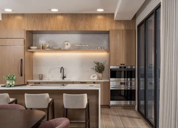 A modern kitchen with a wooden cabinet and a marble backsplash.