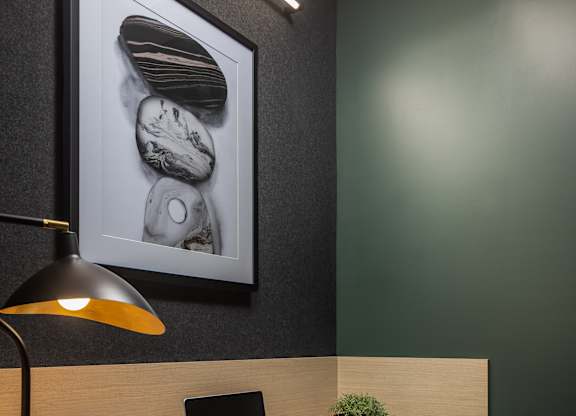 A modern workspace with a laptop, lamp, and a framed picture on the wall.