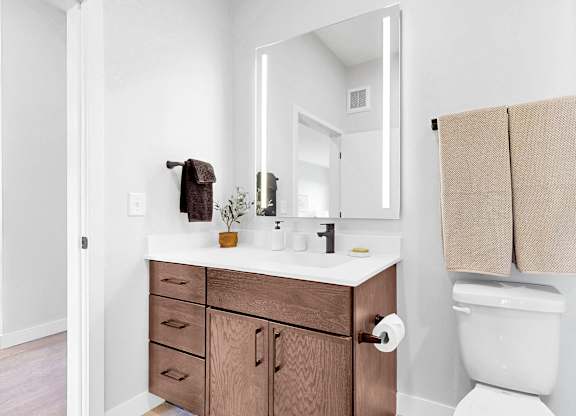 A white toilet sits next to a sink with a mirror above it.