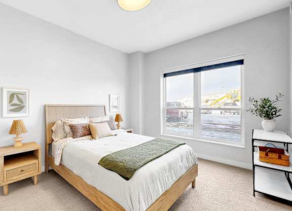 A bedroom with a bed, nightstand, and window.
