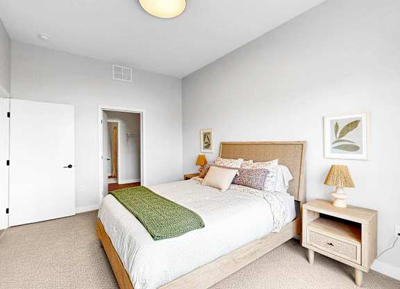 A bedroom with a bed, nightstand, and lamp.