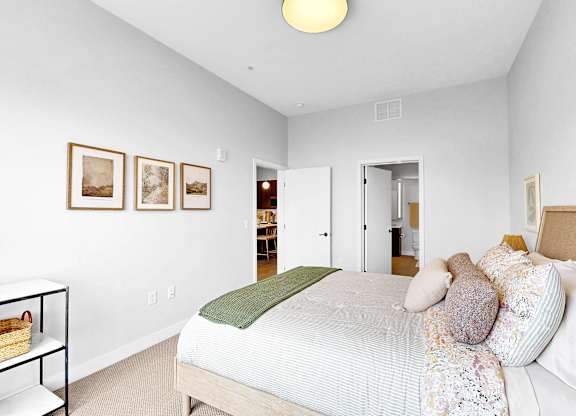 A bedroom with a bed, pillows, and pictures on the wall.