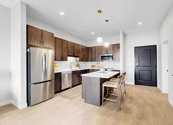 A kitchen with a refrigerator, sink, and a dining table with chairs.