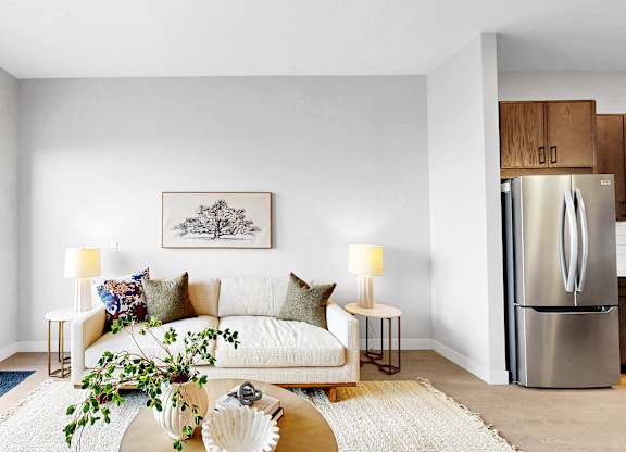 A modern living room with a white couch, a coffee table, and a painting on the wall.