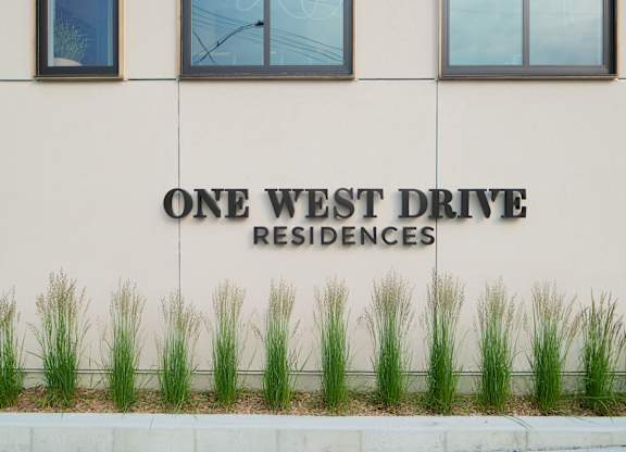 A building with a sign that says "One West Drive Residences".