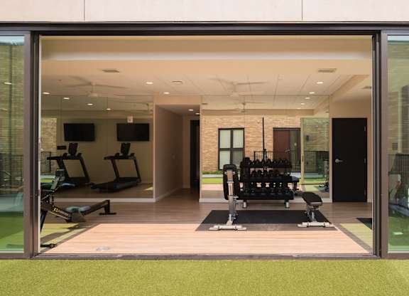 A gym with a green floor and a glass wall.