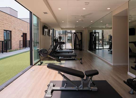 A gym with a variety of equipment including treadmills and weights.