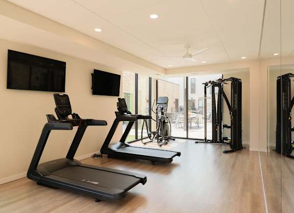 A gym with treadmills, exercise bikes, and a television.