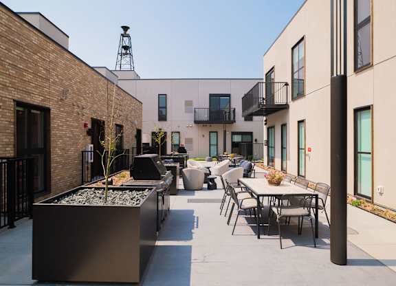 A patio with a table and chairs is surrounded by buildings.