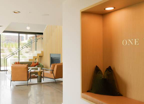 A modern living room with a sofa set and a wooden wall with the words "One West" on it.