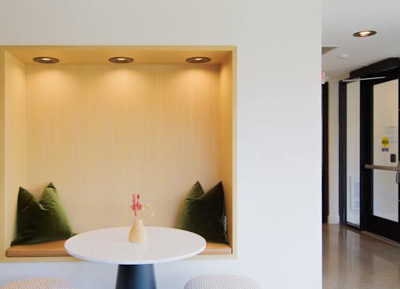 A small table with a vase on it sits in front of a wall with a picture frame.