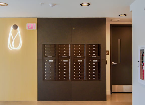 A white exit sign is mounted on a yellow wall.