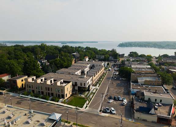 A view of a town with a parking lot in the foreground and a body of water in the background.