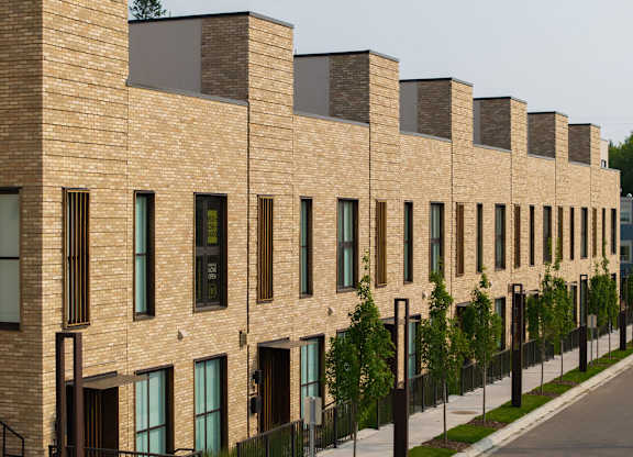 A long row of brown brick houses with black railings.