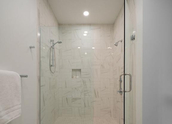 A white tiled shower with a glass door.