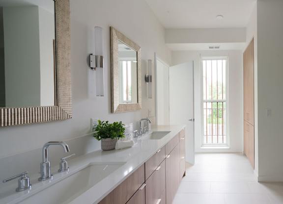 A modern bathroom with a long counter and a large mirror.