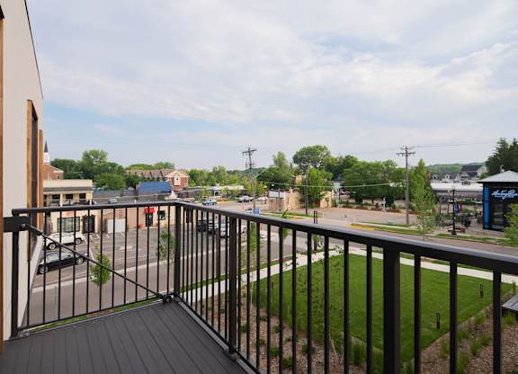 A balcony overlooks a parking lot and buildings.