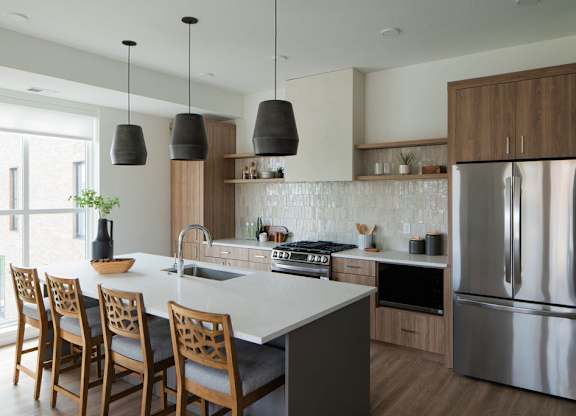 A modern kitchen with a large island and wooden chairs.