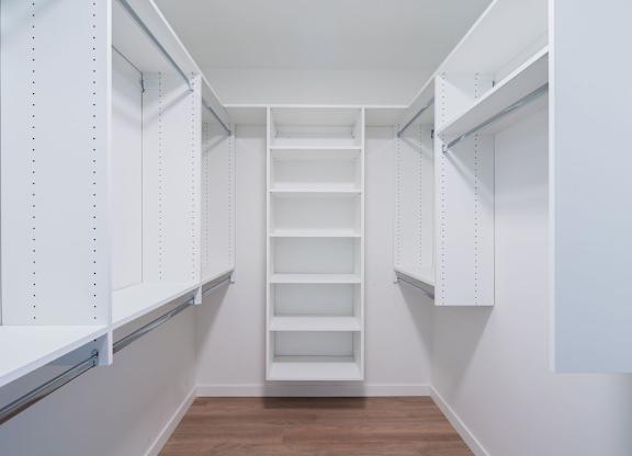A white pantry with a wooden floor and white shelves.