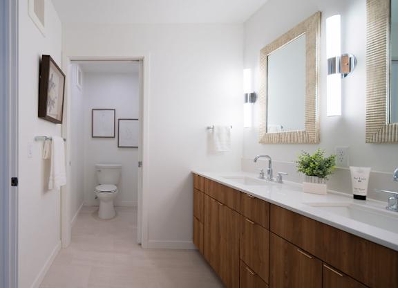 A bathroom with a toilet, sink, and mirror.