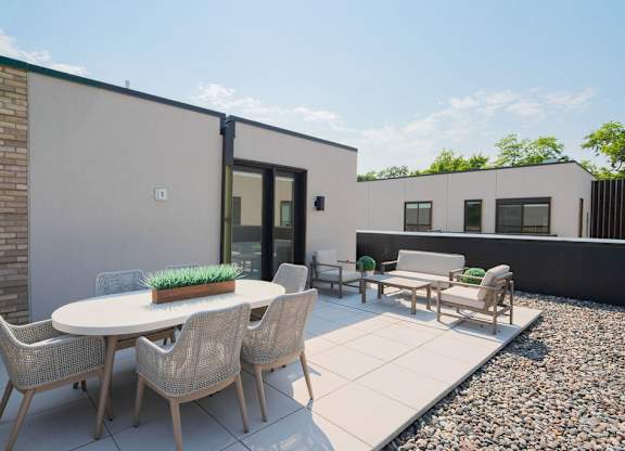 A patio with a table and chairs is surrounded by a gravel area.