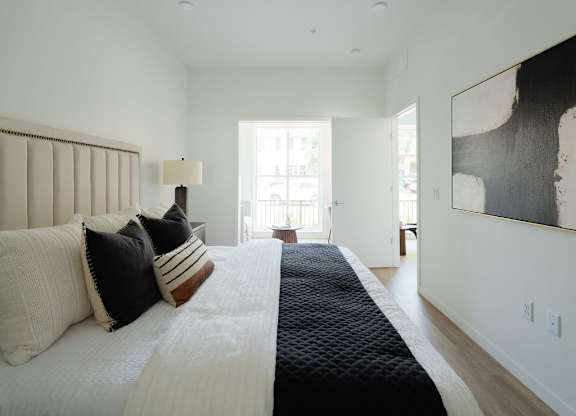 A bedroom with a large bed and a painting on the wall.