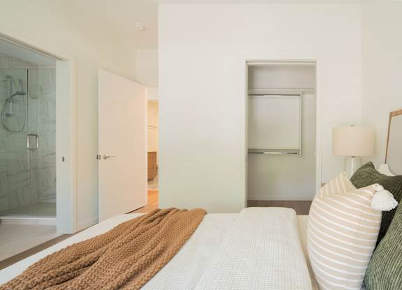 A bedroom with a bed, a nightstand, and a window.