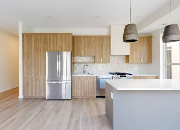 A modern kitchen with wooden cabinets and a white countertop at One West Drive Apartments, Excelsior, 55331